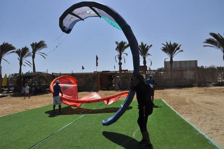 A kite being prepared on the grass at the KiteMood beach base, with palm trees behind