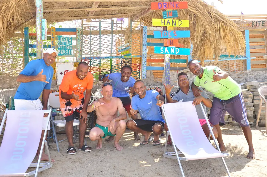 KiteMood team and guests smiling together under the thatched beach lounge