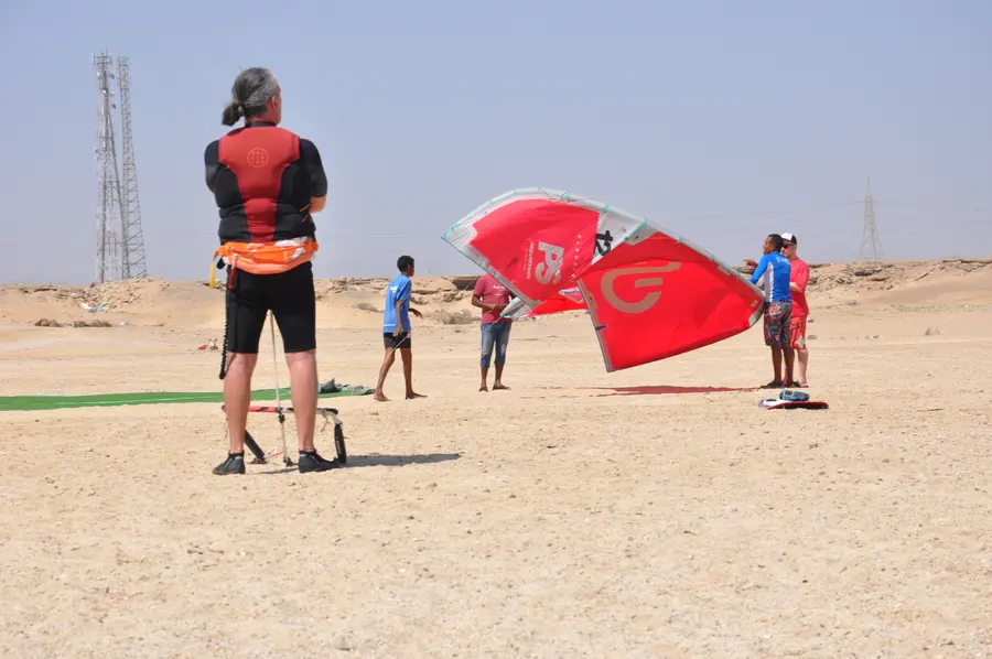 Instructor and students launching a red kite together during a beach lesson at KiteMood Marsa Alam